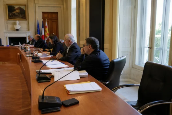 Salle municipale avec micros, dossiers et chaise vide, dans une ambiance de conseil local liée aux incendies en Gironde