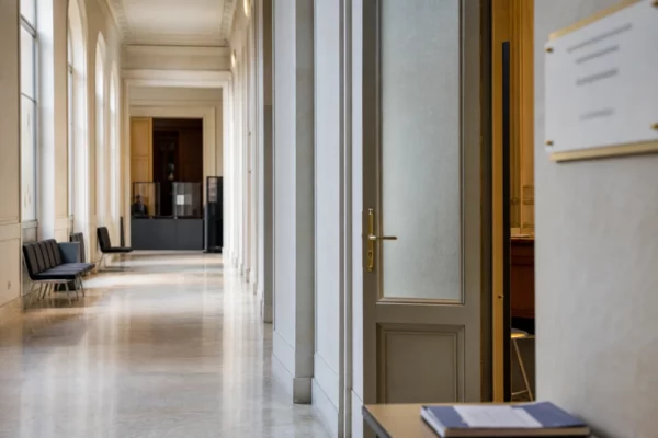 Couloir clair d’une institution française avec porte de salle d’audition et ambiance administrative sobre.