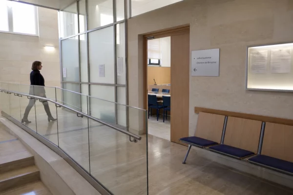 Couloir lumineux d’une institution publique française avec porte d’audition et ambiance de contrôle discret
