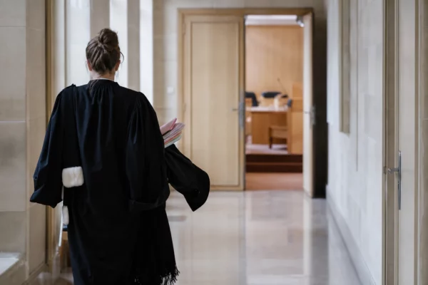 Couloir clair d’un bâtiment institutionnel français avec porte ouverte sur une salle d’audition vide.