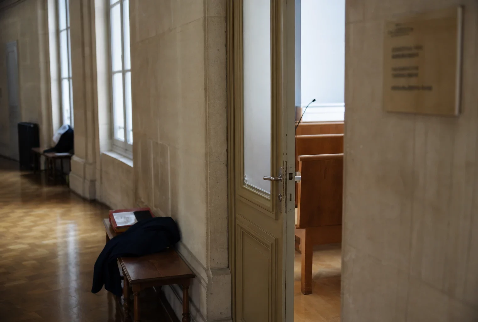 Couloir institutionnel lumineux et vide dans un bâtiment public français, avec porte sobre et lumière naturelle.