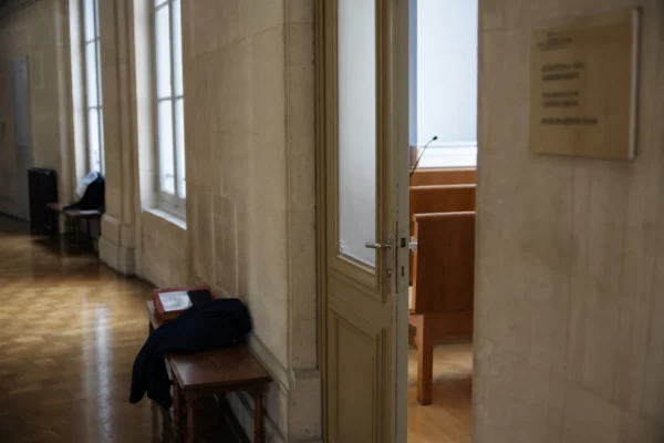 Couloir institutionnel lumineux et vide dans un bâtiment public français, avec porte sobre et lumière naturelle.