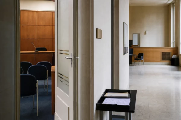 Couloir clair d’un bâtiment institutionnel français menant à une salle d’audition, ambiance sobre et documentaire
