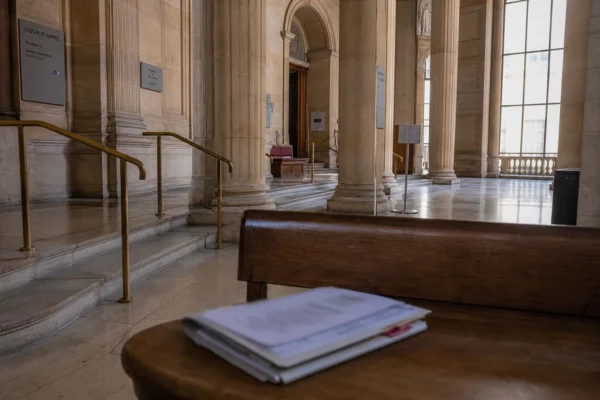 Intérieur lumineux d’une cour d’appel parisienne vide, avec marbre clair et dossier flou sur un banc.