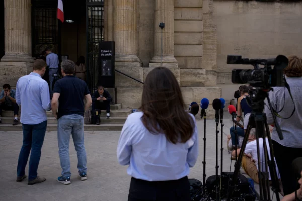 Reportage devant un palais de justice parisien avec journalistes et passants dans une atmosphère calme avant une décision judiciaire.
