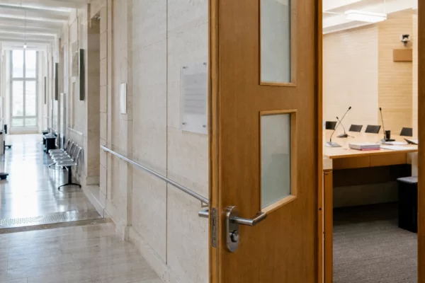 Couloir lumineux d’une institution publique française avec salle d’audition visible en arrière-plan