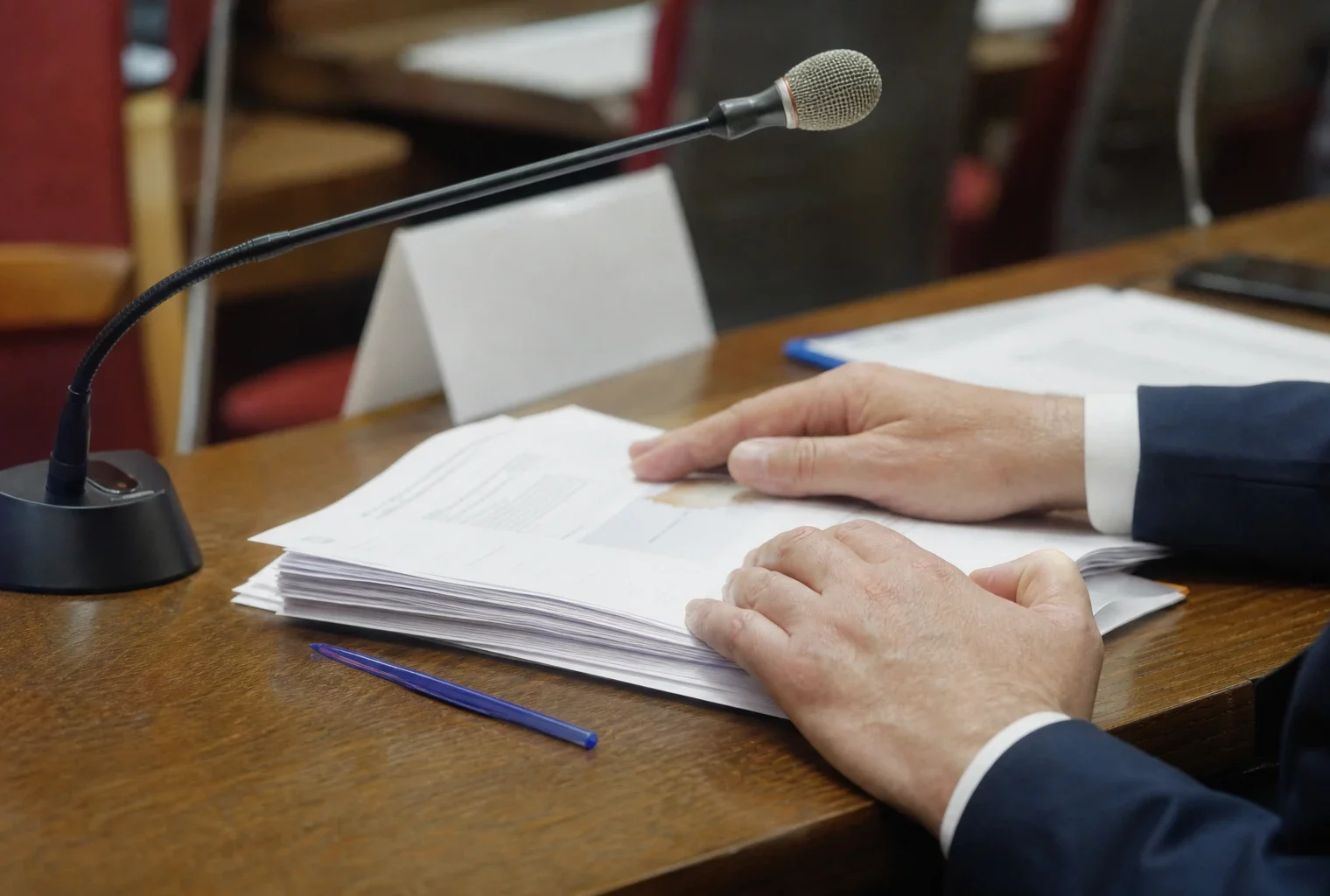 Mains anonymes, micro de commission et documents flous dans une salle parlementaire française