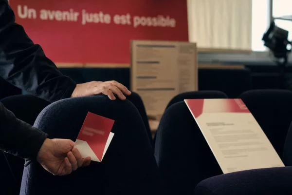 Main sur un fauteuil de salle avec billet flou et programme culturel en arrière-plan, lumière naturelle chaude.
