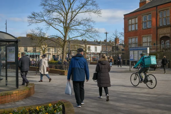 Place de ville moyenne anglaise avec habitants anonymes, mairie locale, arrêt de bus et logements en arrière-plan