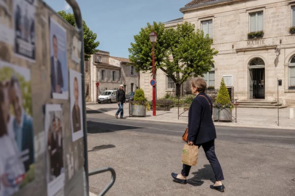 Rue d’une ville moyenne française près de la mairie, passants anonymes et ambiance politique locale discrète.