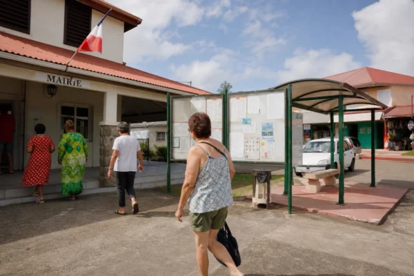 Des habitants anonymes passent devant une mairie de Nouvelle-Calédonie le jour d’une élection provinciale.