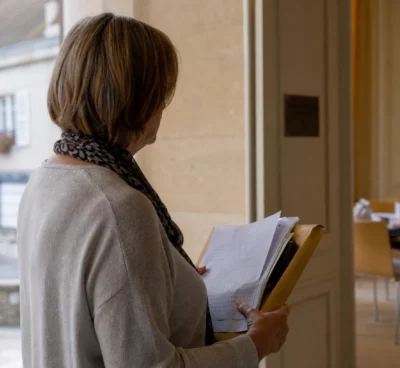 Un élu local anonyme de dos consulte un dossier dans un couloir de mairie, lumière naturelle et ambiance civile.