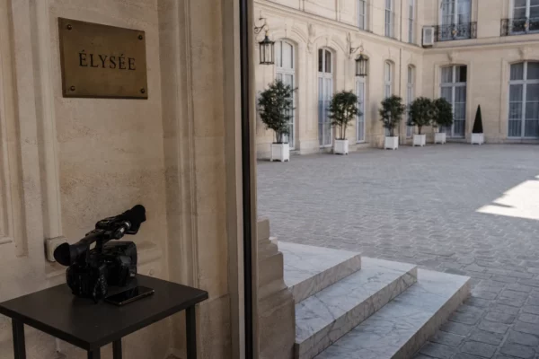 Cour de l’Élysée vide et lumineuse avec une caméra de presse, dans une ambiance institutionnelle discrète.