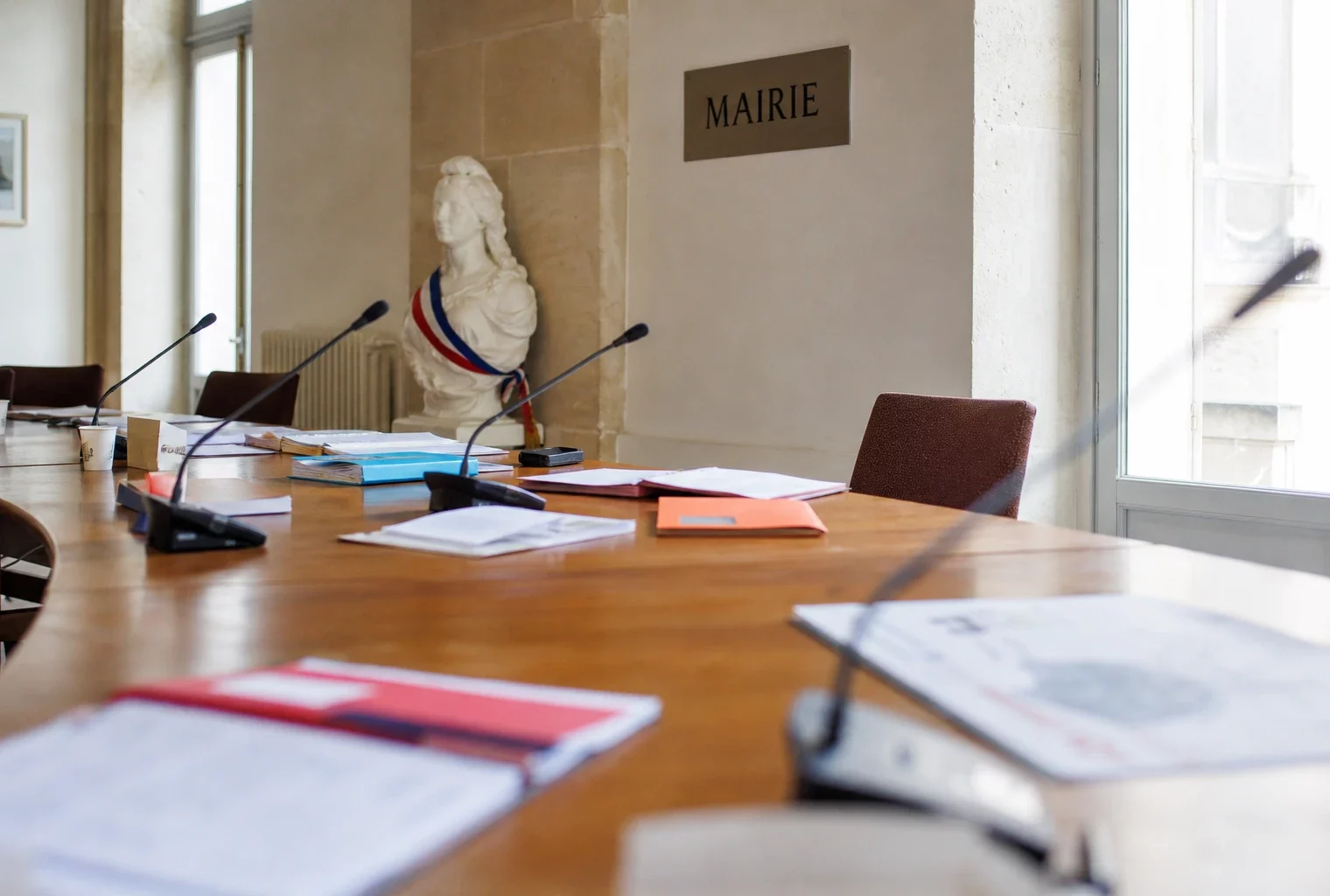 Salle municipale de briefing avec chaise vide, micros et dossiers, en soutien à la gestion des incendies.