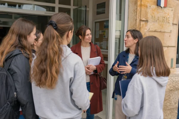 Des collégiennes écoutent une ingénieure devant une mairie, lors d’une rencontre sur les métiers scientifiques.