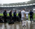 Des journalistes attendent en zone mixte après un match de Coupe du monde 2026, avec des joueurs anonymes au stade.