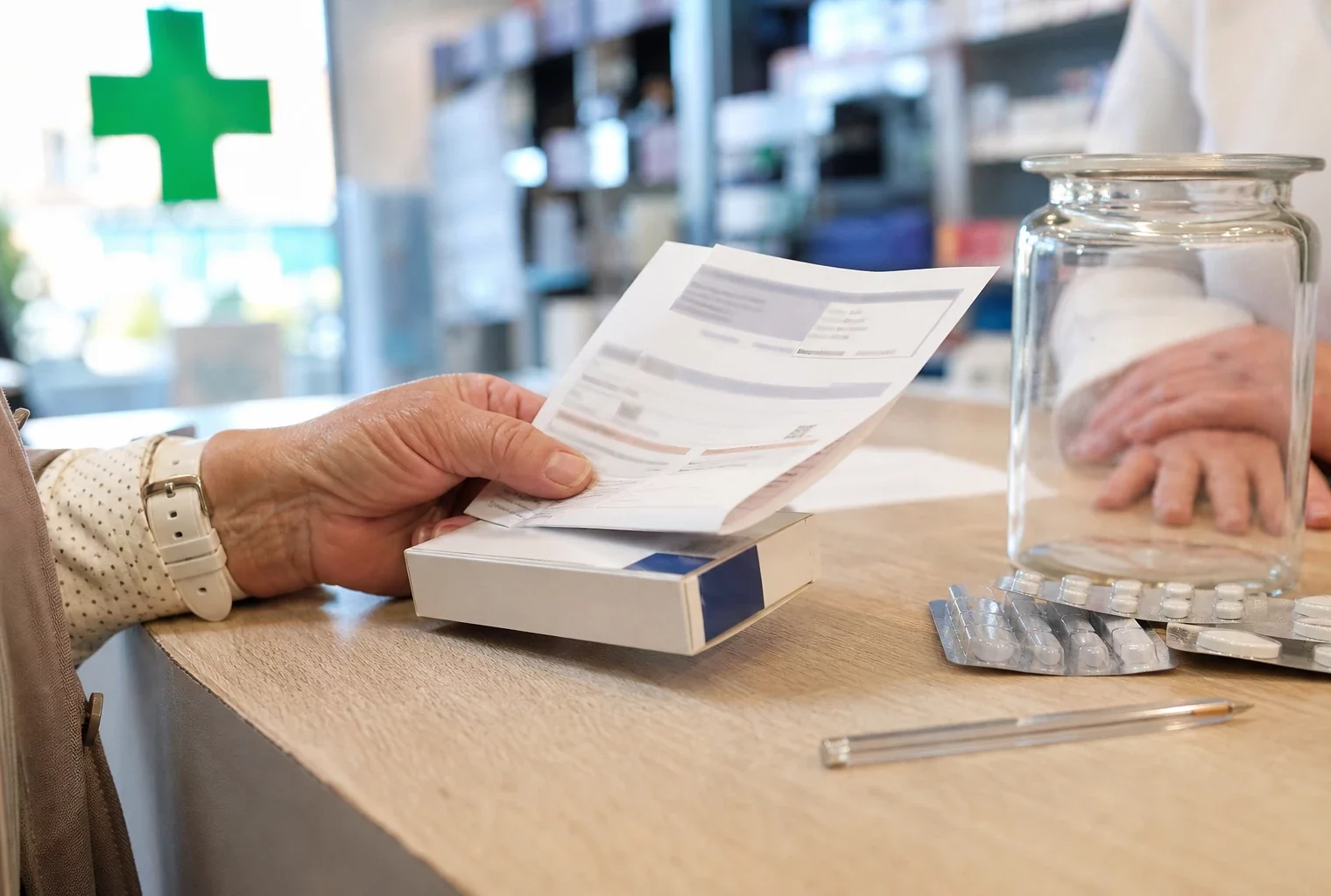 Gros plan dans une pharmacie française sur une main tenant un reçu et une boîte de médicament