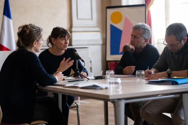 Réunion municipale à Grenoble autour du Cabaret Frappé, avec plusieurs personnes en briefing et micro sur la table.
