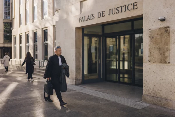 Façade du palais de justice de Grenoble avec passants anonymes devant l’entrée, en lumière naturelle claire.