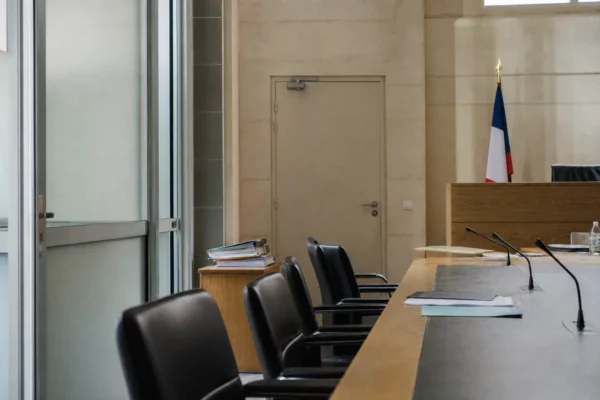 Salle d’audition institutionnelle lumineuse et vide, avec tables, chaises et dossiers flous dans un cadre français neutre.