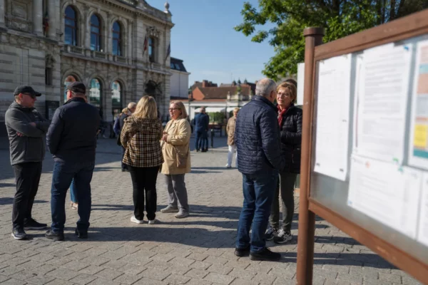 Des habitants discutent sur une place de Hénin-Beaumont devant la mairie, dans une ambiance de reportage calme.