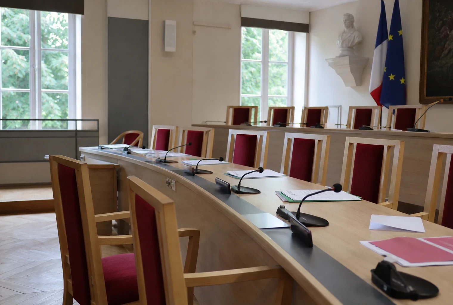 Salle municipale française avec micros et dossiers flous, chaise vide, ambiance sobre liée aux incendies de Fontainebleau