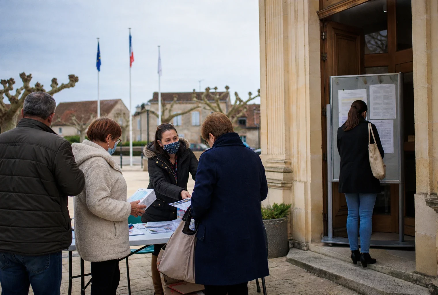 Des habitants et un agent municipal devant une mairie en Gironde, dans une ambiance claire liée aux fumées de l’incendie.