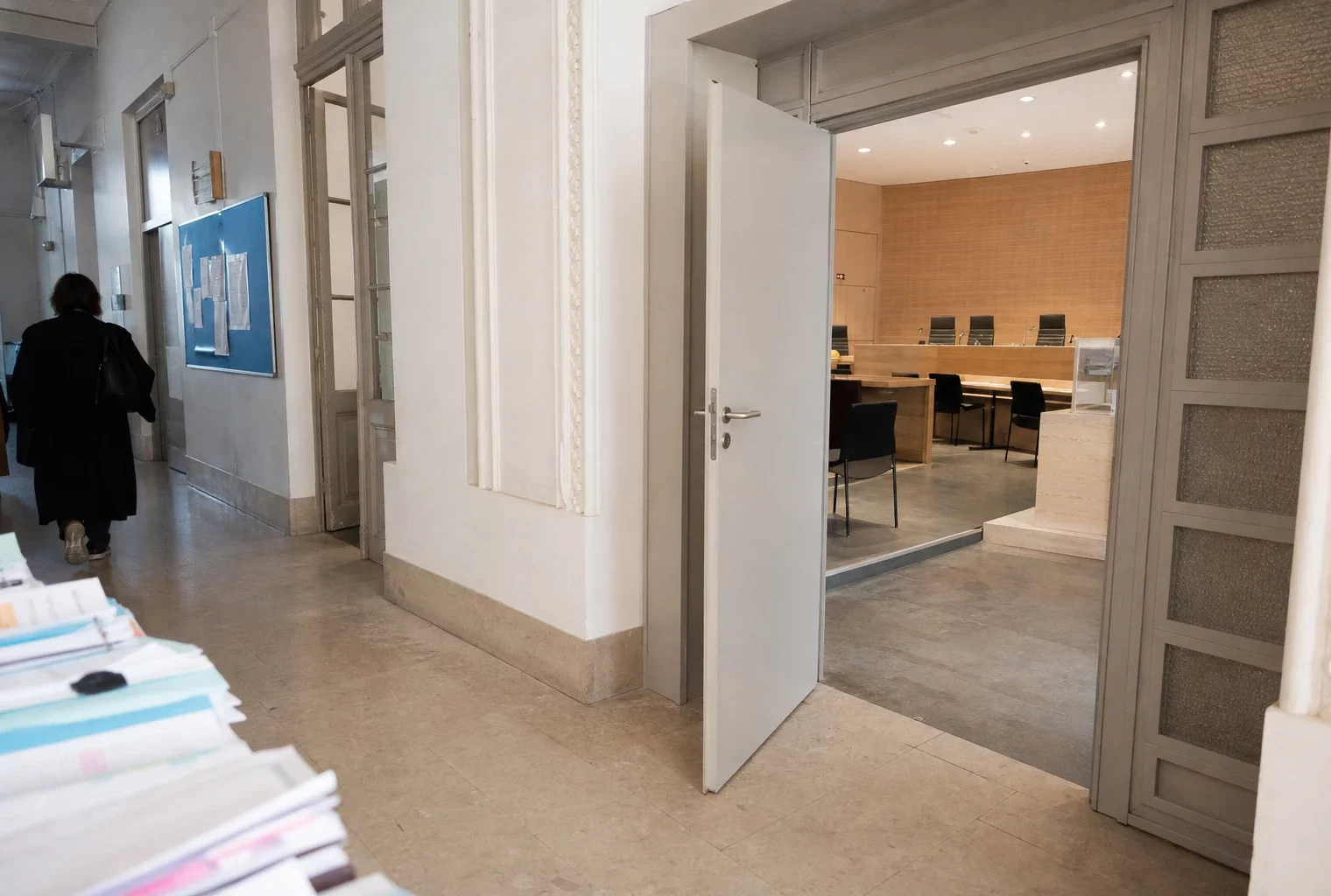 Couloir clair d’un bâtiment institutionnel français, porte sobre et salle d’audition vide en arrière-plan