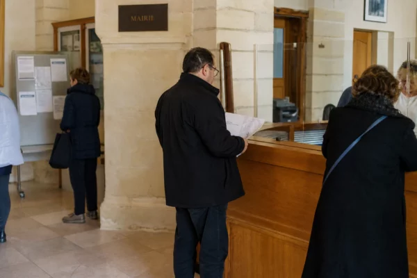 Accueil lumineux d’une mairie française avec des usagers anonymes et un comptoir de service public.