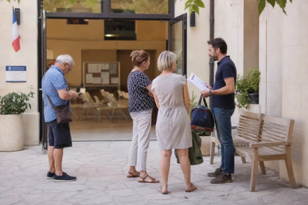 Des habitants attendent devant une mairie après une alerte incendie, dans une scène de reportage civique en lumière naturelle.