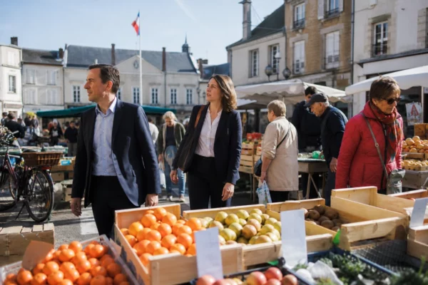 Reportage photo d’un marché de ville française avec deux responsables politiques anonymes au milieu des passants.