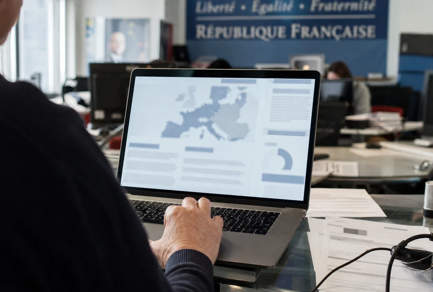 Vue de dos dans une rédaction française, un écran d’ordinateur affiche une interface abstraite avant le verdict de Marine Le Pen.