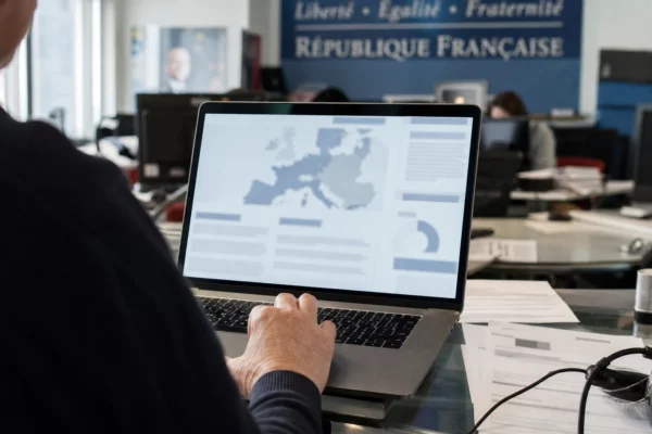 Vue de dos dans une rédaction française, un écran d’ordinateur affiche une interface abstraite avant le verdict de Marine Le Pen.