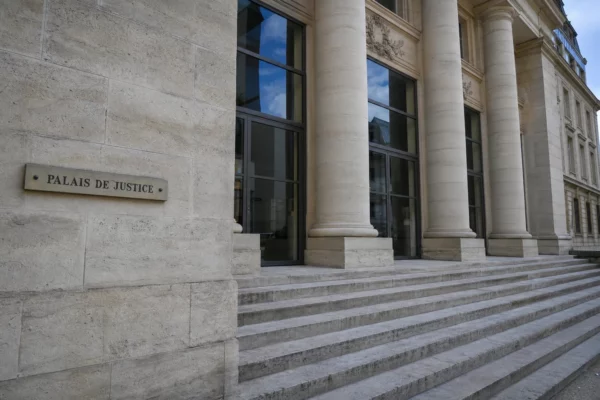 Façade du palais de justice à Paris, vue oblique et lumineuse, dans une ambiance institutionnelle calme.