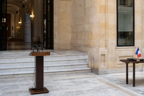 Cour institutionnelle à Damas avec pupitre de presse et ambiance diplomatique, en lumière claire et naturelle.