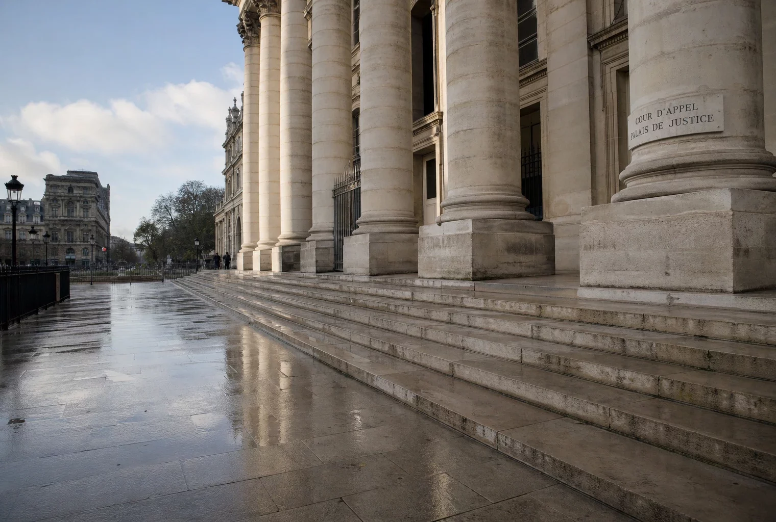 Façade du Palais de justice de Paris au matin, avec marches humides et ambiance institutionnelle calme