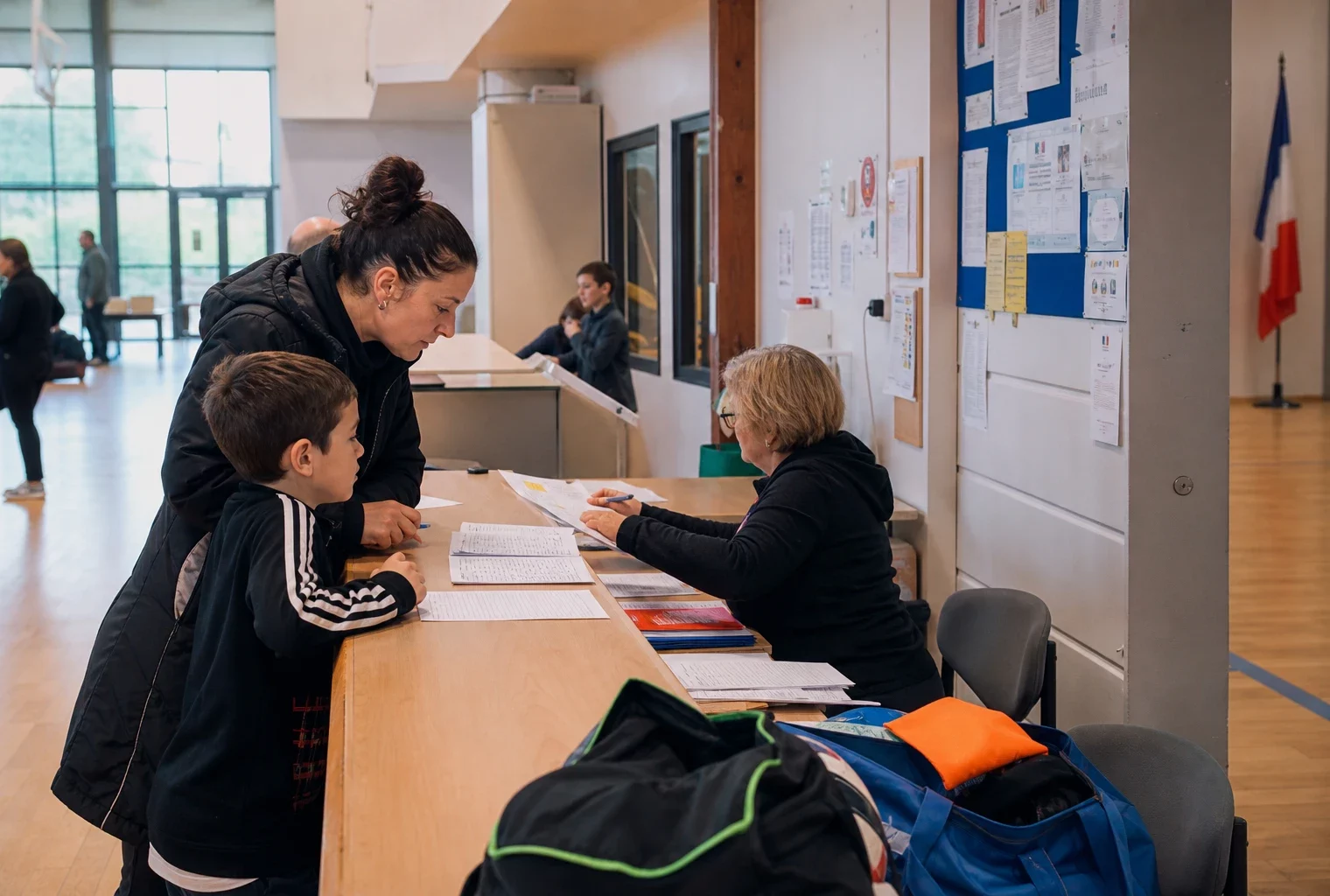Des parents inscrivent leur enfant dans un club de sport, dans un hall lumineux de mairie, avec un bénévole au comptoir.