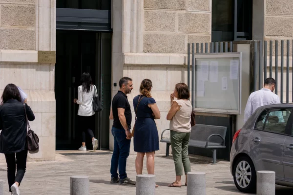 Cour calme devant un bâtiment de sécurité publique en France, avec des passants anonymes et une ambiance de reportage