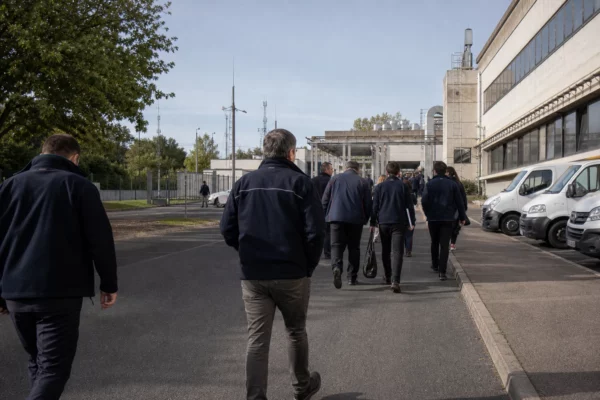Des techniciens anonymes devant un bâtiment de recherche lié à la défense, dans une scène calme de reportage.