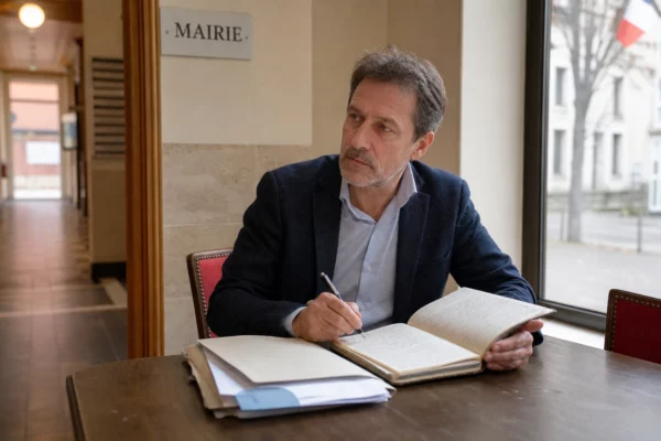 Portrait photojournalistique d’un élu local anonyme prenant des notes dans une mairie, lumière naturelle douce.