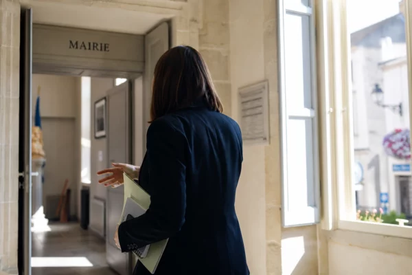 Portrait d’un élu local anonyme dans une mairie française, dossier en main, ambiance civique et lumineuse.