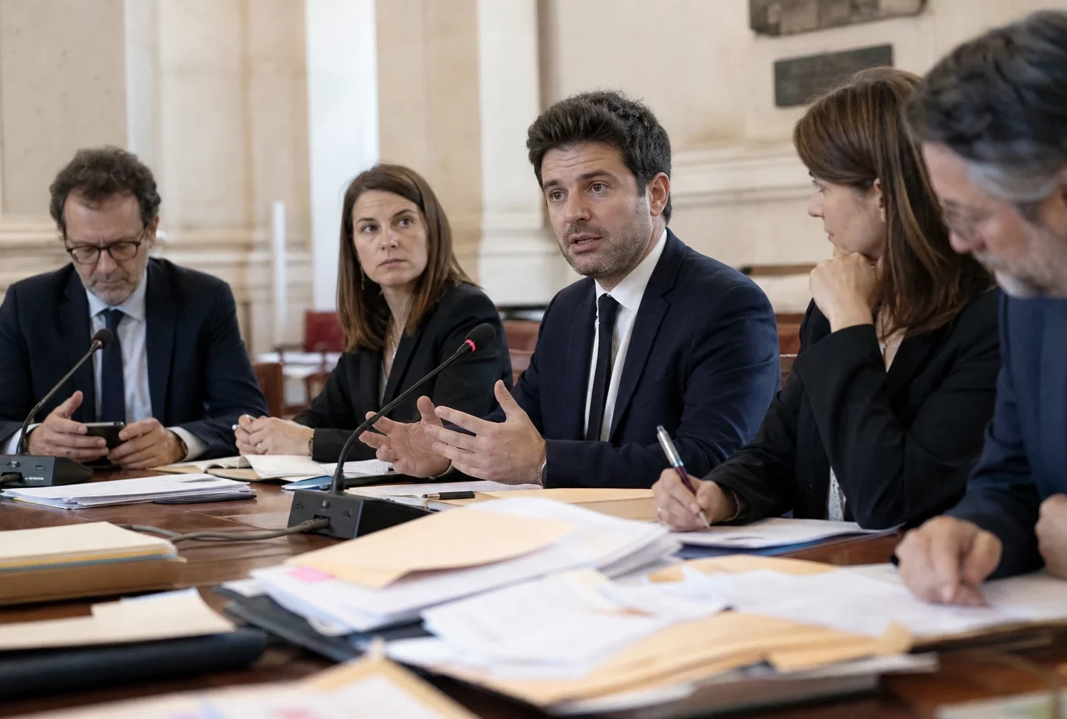 Réunion de juristes et d’aides politiques dans une salle institutionnelle parisienne autour d’un dossier de recours.