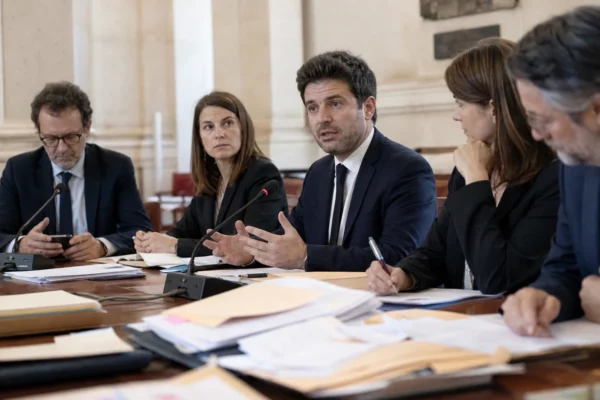 Réunion de juristes et d’aides politiques dans une salle institutionnelle parisienne autour d’un dossier de recours.