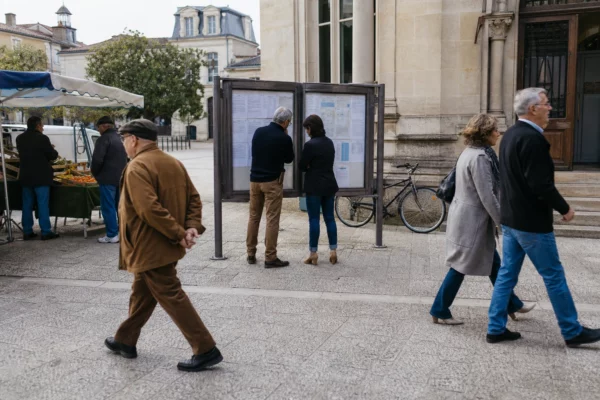 Scène de rue française devant une mairie, avec passants anonymes et ambiance locale calme