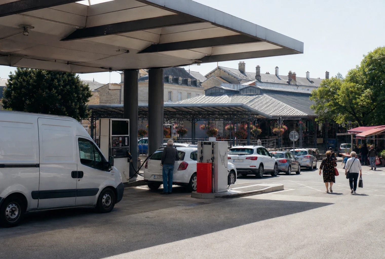Reportage dans une ville française, devant une station-service générique avec des automobilistes et passants anonymes.