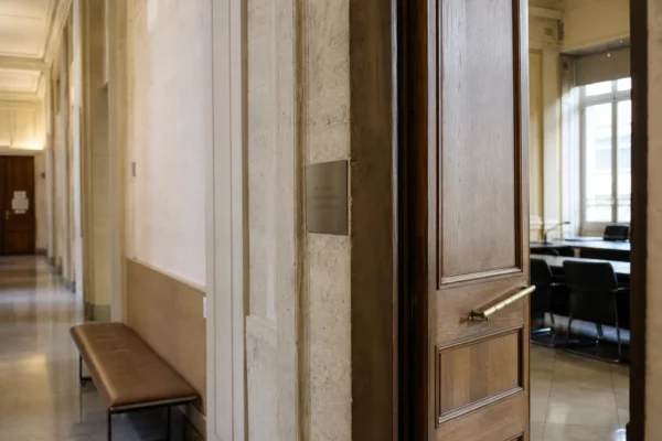 Couloir clair d’un bâtiment institutionnel français, porte sobre et salle d’audition en lumière naturelle