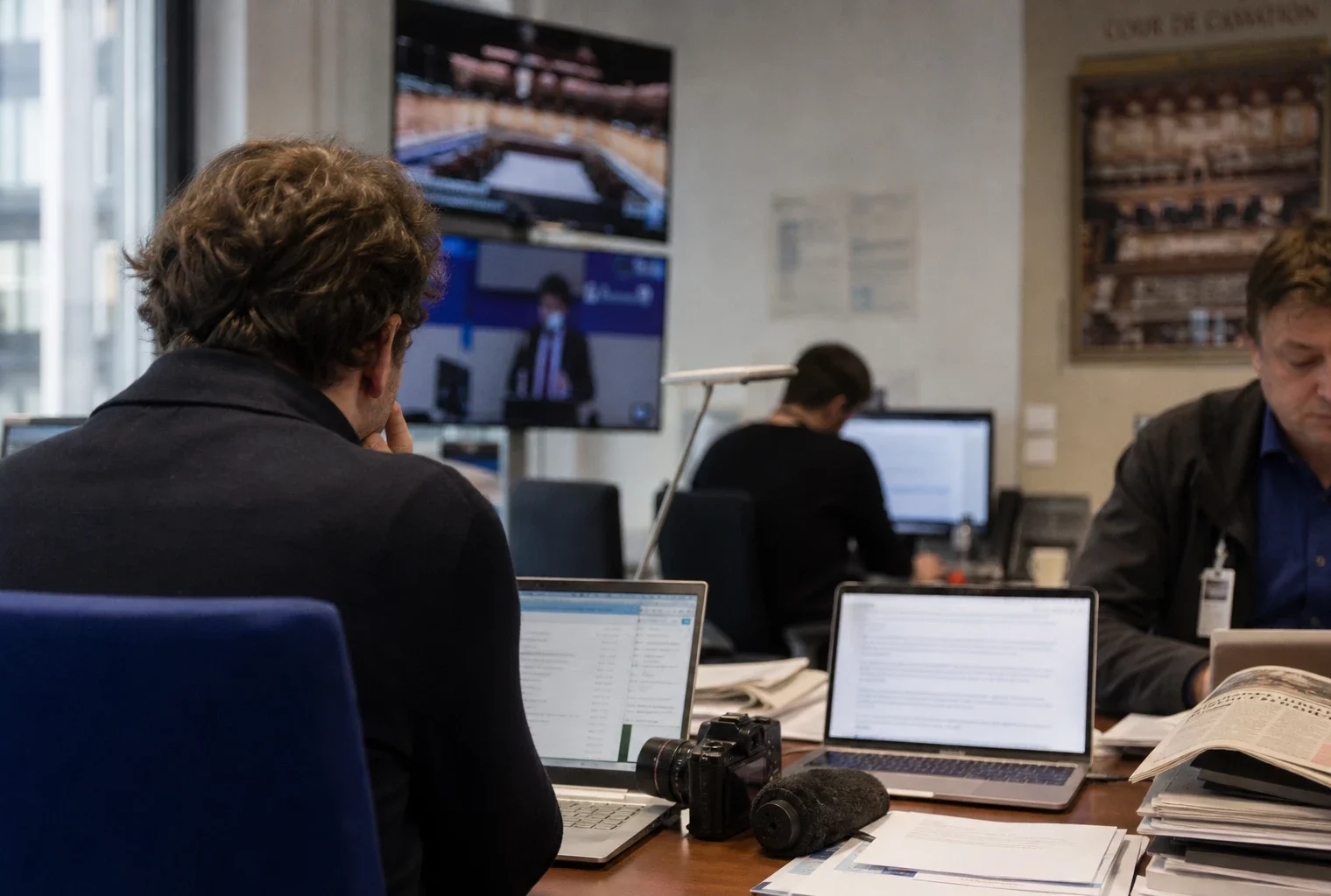 Rédaction française avec journaliste, micros et écrans flous autour d’un dossier judiciaire politique.