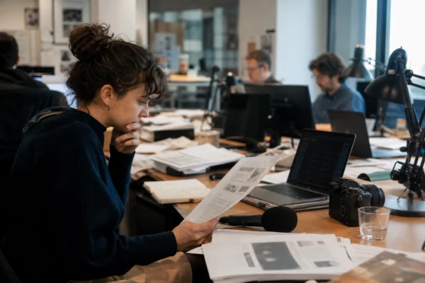 Rédaction française avec un journaliste, des documents flous et un micro, en pleine préparation d’un sujet politique.