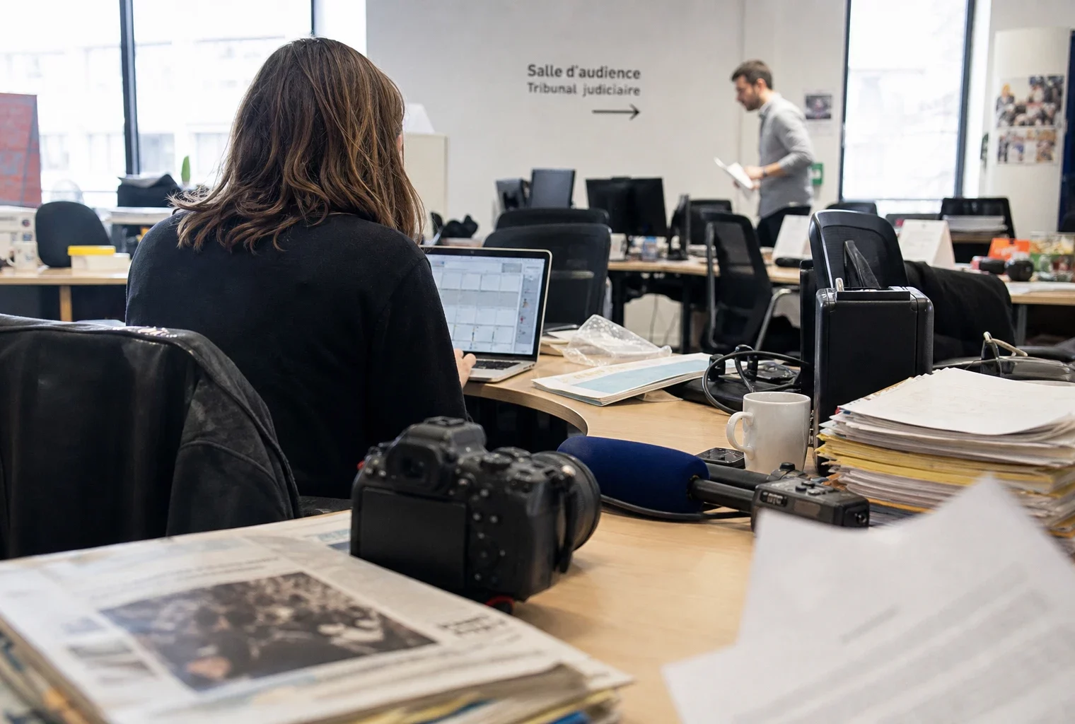 Journaliste dans une rédaction française avec caméra, micro et documents de tribunal flous