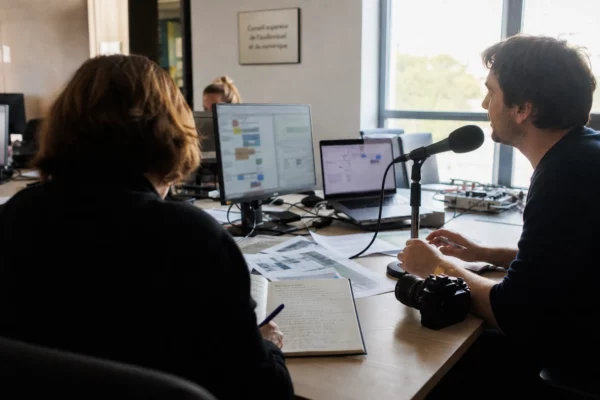 Rédaction française en activité avec journaliste, micro et écrans flous pour illustrer la bataille médiatique avant la présidentielle